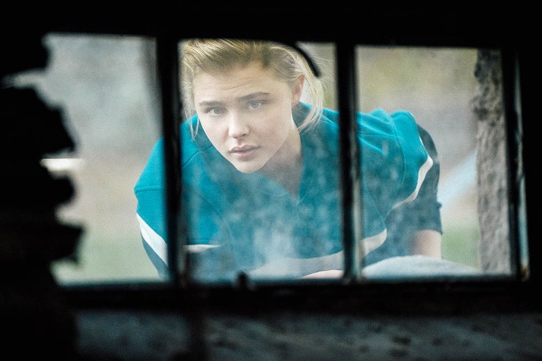 A young woman peers through a window.